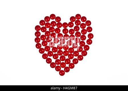 Forma di cuore creati al di fuori di compresse di colore rosso su sfondo bianco simboleggia il cuore farmaci o il romanticismo e il giorno di san valentino valentin Foto Stock