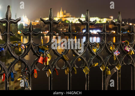 Molti amano le serrature sulla recinzione, cuore lucchetto sul Ponte Carlo a Praga il Hradcany sfondo sfocato. Amore serrature da appendere Foto Stock