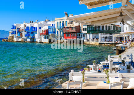 Dal Porto di Mykonos, Grecia - 16 Maggio 2016: tabelle di un ristorante sulla passeggiata costiera nella piccola Venezia parte della città di Mykonos, Grecia. Foto Stock