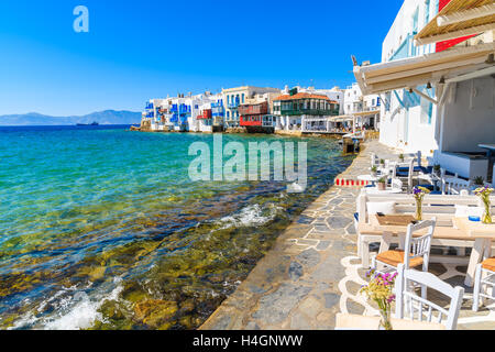 Sedie e tavoli in tipica taverna greca nella piccola Venezia parte della città di Mykonos, a Mykonos, Grecia Foto Stock