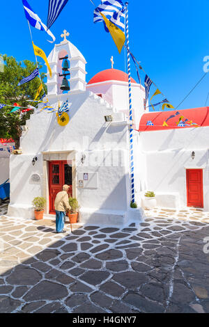 La città di Mykonos, Grecia - 16 Maggio 2016: il greco antico uomo in piedi di fronte ad una chiesa e guardando necrologi, Mykonos, Cyclad Foto Stock