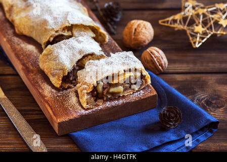 Natale dolci fatti in casa. Strudel di mele (torta) con uvetta, noci e zucchero in polvere con decorazioni di Natale vicino. Foto Stock