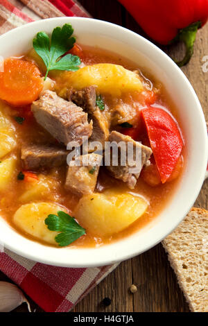 In casa gustoso stufato con la carne e le verdure nella ciotola con gli ingredienti su tavola in legno rustico Foto Stock