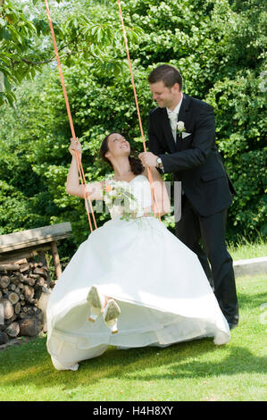 Coppia di sposi, sposa seduto su uno swing Foto Stock