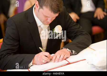 Lo sposo firma il certificato di matrimonio presso l ufficio del registro di sistema Foto Stock