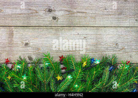 Natale abete del ramo decorato con ghirlande di luci su sfondo di legno Foto Stock