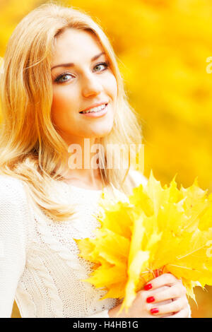 Sorridente bella giovane donna con grappolo di foglie in autunno park Foto Stock