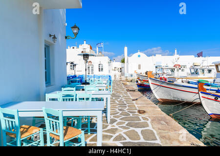 Taverna tavoli e tipico greco barche da pesca nel porto di Naoussa, isola di Paros, Cicladi Grecia Foto Stock