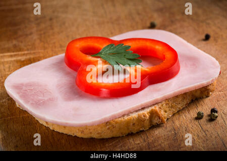 Fetta di pane con prosciutto crudo fresco e pepe rosso su sfondo di legno Foto Stock