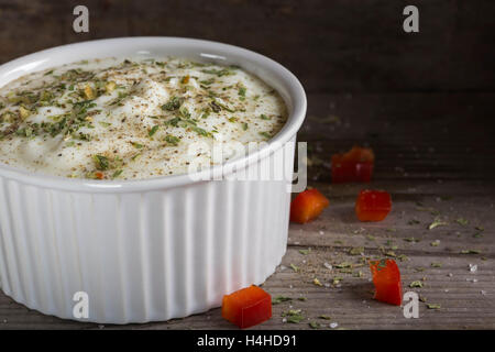 Salsa a base di yogurt e di erbe e di pepe nero in ciotola su una tavola di legno Foto Stock