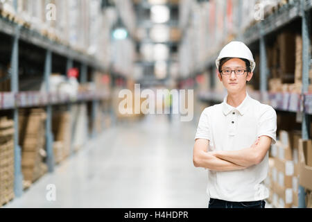 Bel giovane ingegnere asiatici o il tecnico o lavoratore, in magazzino o in fabbrica blur sullo sfondo, industria o concetto logistico, con Foto Stock