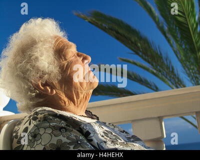 Donna anziana si rilassa con soddisfazione nel caldo sole nella sua villa per le vacanze home Foto Stock