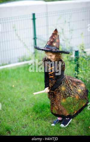 Preparazione per la festa di Halloween. La ragazza in un abito della strega finge che lei vola sulla scopa. La ragazza è vestito con una b Foto Stock