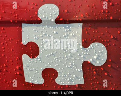 Colore bianco o grigio puzzle pezzo scuro su sfondo rosso con gocce di pioggia. Puzzle pezzo decalcomania metallico Foto Stock
