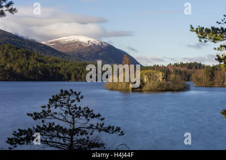 Vista sul Loch un Eilein mostrando la sua isola con un castello rovina e coperti di neve montagna in background Foto Stock