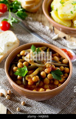 Vegetariano stufato di verdure con ceci e fagioli verdi su sfondo rustico, mangiare sano, dieta, cucina vegetariana e th Foto Stock