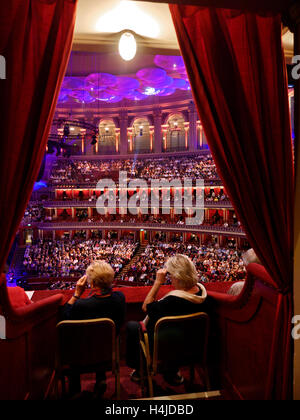 Due signore guardando una performance attraverso l opera bicchieri in un morbido velluto rosso box presso la Royal Albert Hall di Londra Kensington Foto Stock