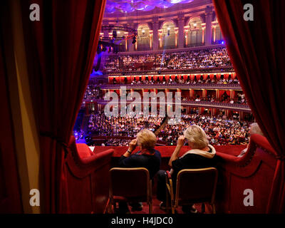 ALBERT HALL interno due signore guardando una performance attraverso l opera bicchieri in velluto rosso box privato presso la Royal Albert Hall di Londra Kensington Foto Stock