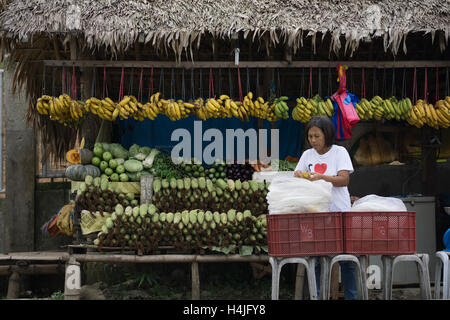 Una donna in piedi di fronte ad una strada di frutta e verdura,stallo Cebu, Filippine. Foto Stock