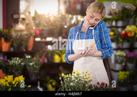 Fiorista femminile prendendo un ordine sul telefono cellulare Foto Stock