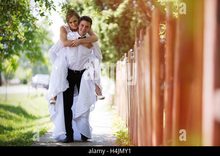 Lo sposo che trasportano sposa piggyback e divertirsi Foto Stock