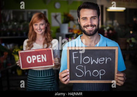 Uomo con ardesia con negozio di fiori segno e donna tenendo aperte cartello Foto Stock