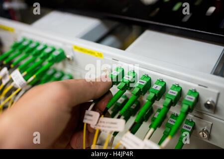 Il tecnico collegando il cavo patch in un rack server Foto Stock