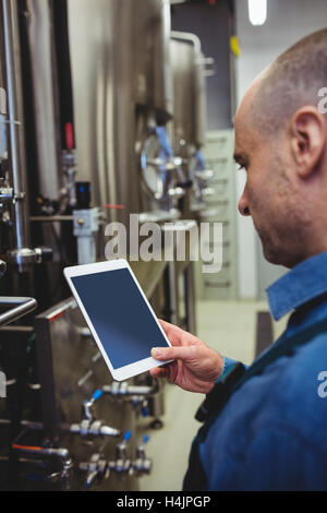 Proprietario maschio utilizzando tavoletta digitale presso la fabbrica di birra Foto Stock