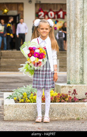 Coltivatore Baby girl prima-grader con un mazzo di fiori alla scuola Foto Stock