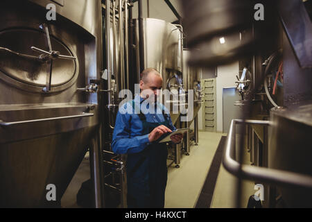 Proprietario utilizzando tavoletta digitale presso la fabbrica di birra Foto Stock