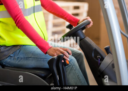 La sezione centrale del lavoratore di magazzino utilizzando un carrello elevatore a forche Foto Stock