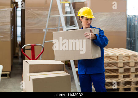 Lavoratore di consegna lo scarico di scatole di cartone dal martinetto pallet Foto Stock