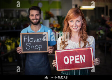 Donna che mantiene aperto cartello e uomo azienda ardesia con negozio di fiori segno Foto Stock