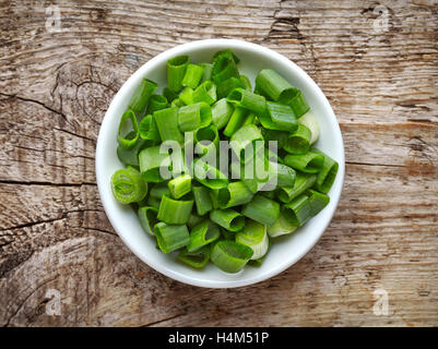 Ciotola di cipolline tagliate su un tavolo di legno, vista dall'alto Foto Stock