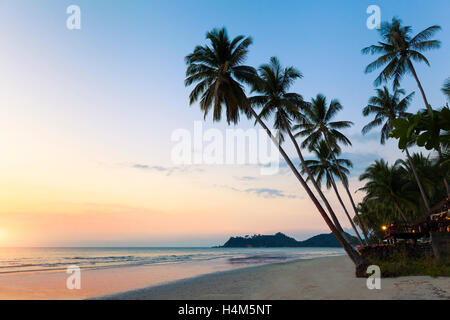 Bella spiaggia tropicale paesaggistico, palme, mare, resort e al tramonto Foto Stock