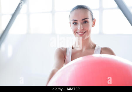 Bella donna felice tenendo un rosa sfera fitness Foto Stock