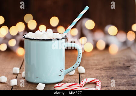 Smalto tazza di cioccolata calda con mini marshmallows e candy canne in forma di cuore contro un sfondo rustico, Foto Stock