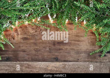 Albero di natale di rami di pino e luci decorative su un sfondo rustico di legno del granaio. Immagine ripresa dalla testa. Foto Stock