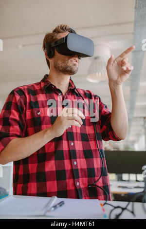 Giovane uomo che indossa occhiali per realtà virtuale e gesticolando. Sviluppatore di realtà virtuale auricolare simulatore. Foto Stock