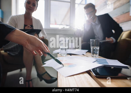 Colpo di gente di affari in una riunione in ufficio, con la donna rivolta a grafici. Professionista aziendale discutendo growt finanziario Foto Stock