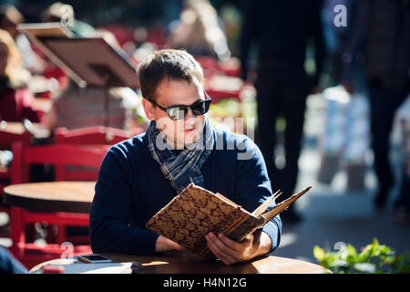 Giovane uomo bello guardare il menu all'aperto Foto Stock