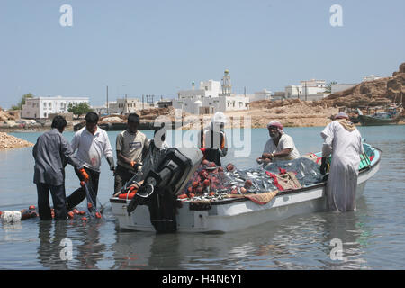 I pescatori locali scaricano la loro piccola barca a Sur in Oman Foto Stock