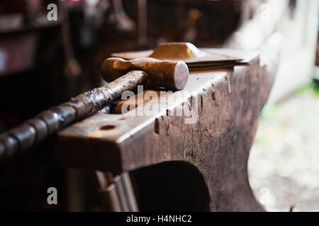 Close up di un martello metallico giacente su incudine in un fabbro della bottega. Foto Stock