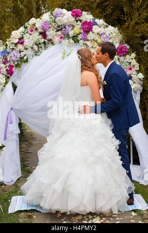 Sposi novelli in piedi vicino all'arco di nozze Foto Stock