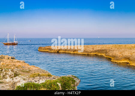 Nave a vela e la costa di Polignano in Puglia in Italia Foto Stock
