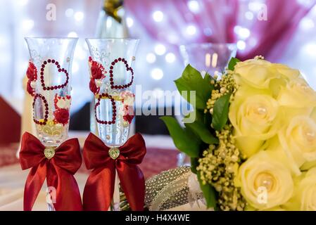 Il giallo della sposa con bouquet nozze due bicchieri di vino decorate con cuori. Decorazioni per matrimoni Foto Stock