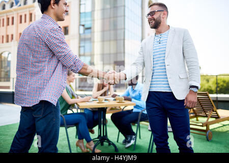 Due giovani imprenditori all'aperto di handshaking Foto Stock