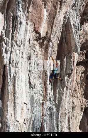 Bionda alpinista femmina verticale ascendente Orange Rock Foto Stock