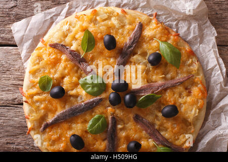 Francese Pissaladiere pizza con le acciughe, olive e cipolla vicino sul tavolo. Orizzontale vista superiore Foto Stock