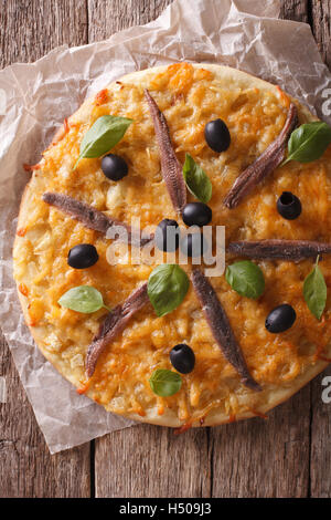 Francese Pissaladiere pizza con le acciughe, olive e cipolla vicino sul tavolo. verticale vista superiore Foto Stock